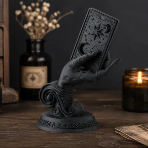 Sculpture main de sorcière noire tenant une carte de tarot dans un décor ésotérique